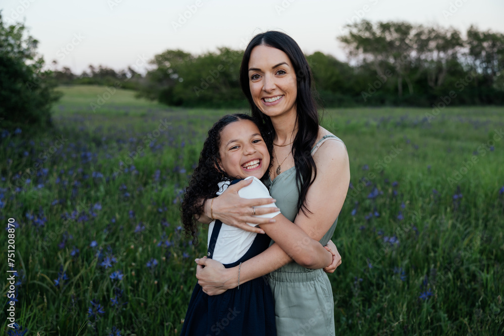 A mother and daughter smile, hugging in green landscape. A mother and daughter smile, hugging in green landscape.