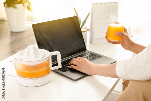 Drinking orange juice while working on laptop