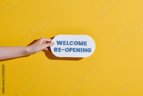 Hand-holding cardboard with as sign welcome reopening photo