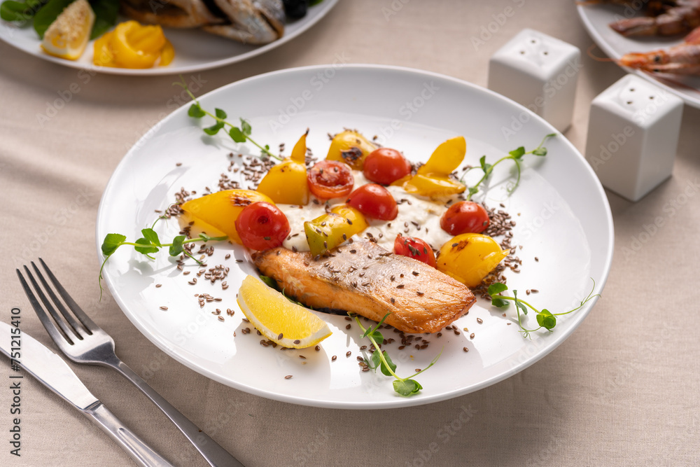 Baked salmon served with tomatoes grill, lemon and microgreen on white plate Baked salmon served with tomatoes grill, lemon and microgreen on white plate