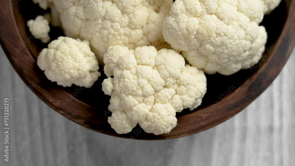 Fresh cauliflower in wooden bowl. Raw vegetable dietary ingredients close up. Rotation Fresh cauliflower in wooden bowl. Raw vegetable dietary ingredients close up. Rotation