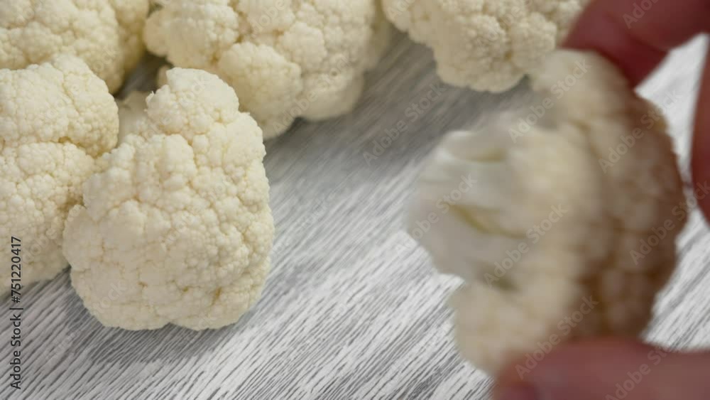 Chef hand takes a bunch of cauliflower close up. Cooking cruciferous vegetables on a diet concept Chef hand takes a bunch of cauliflower close up. Cooking cruciferous vegetables on a diet concept