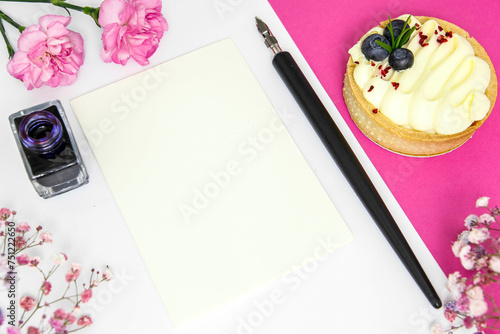 Czysta kartka papieru - miejsce na tekst, pióro, kwiaty i deser.