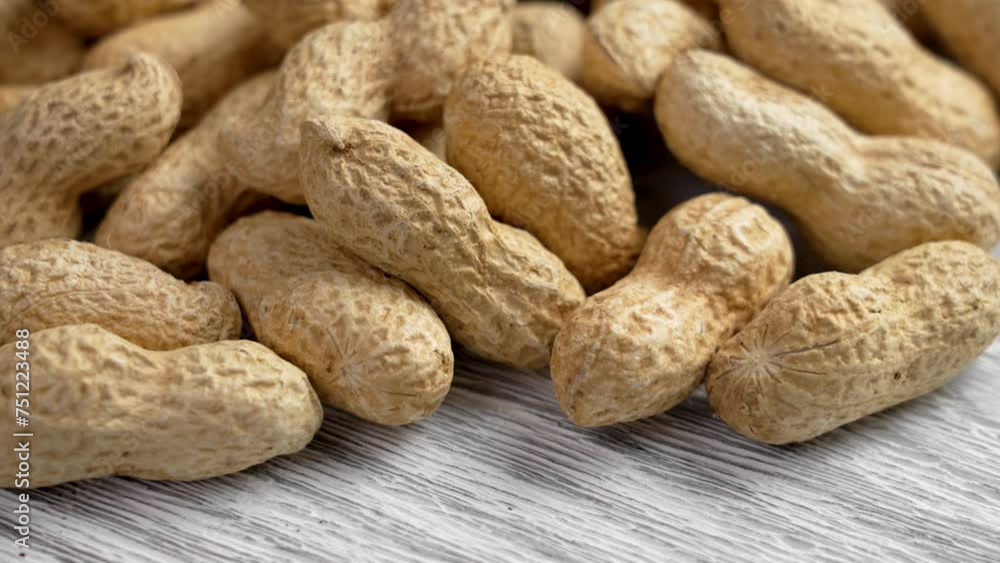 Organic peanuts in nutshell on a rough textured wooden surface close up. Unpeeled roasted ecological groundnuts. Rotation Organic peanuts in nutshell on a rough textured wooden surface close up. Unpeeled roasted ecological groundnuts. Rotation