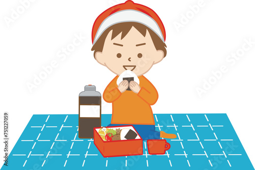 レジャーシートを広げておにぎりを食べる小さな男の子