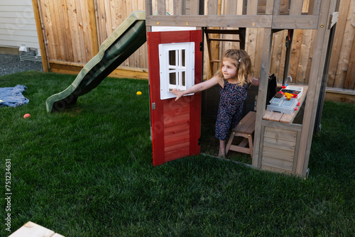 Young in playhouse using her imagination outside. photo