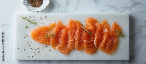 A white cutting board is displayed with neatly arranged slices of salted salmon, placed on a white dish. The fish is meticulously sliced and ready for consumption.