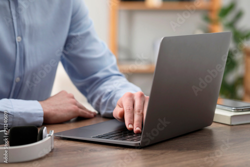 E-learning. Man using laptop during online lesson at table indoors, closeup