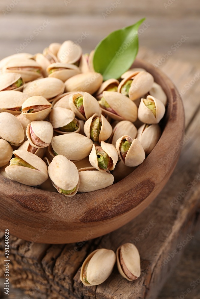 Delicious pistachios in bowl on wooden table, closeup Delicious pistachios in bowl on wooden table, closeup
