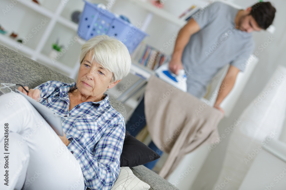 Obraz premium senior reading book on the sofa carer ironing