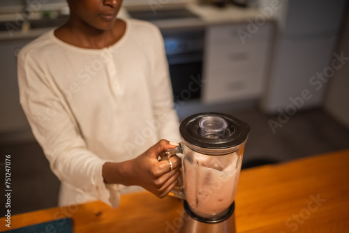Crop black woman mixing milkshake with blender photo