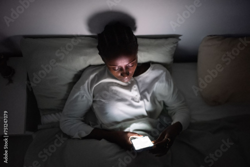Woman messaging on smartphone late at night photo
