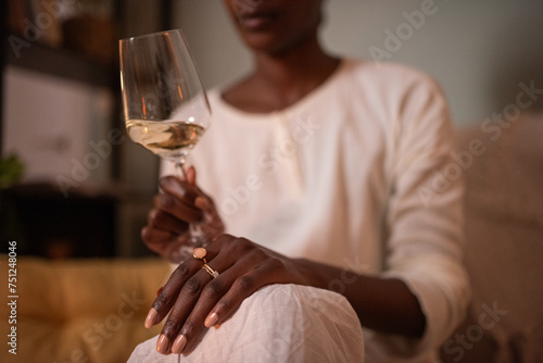 Crop black woman holding glass of white wine photo