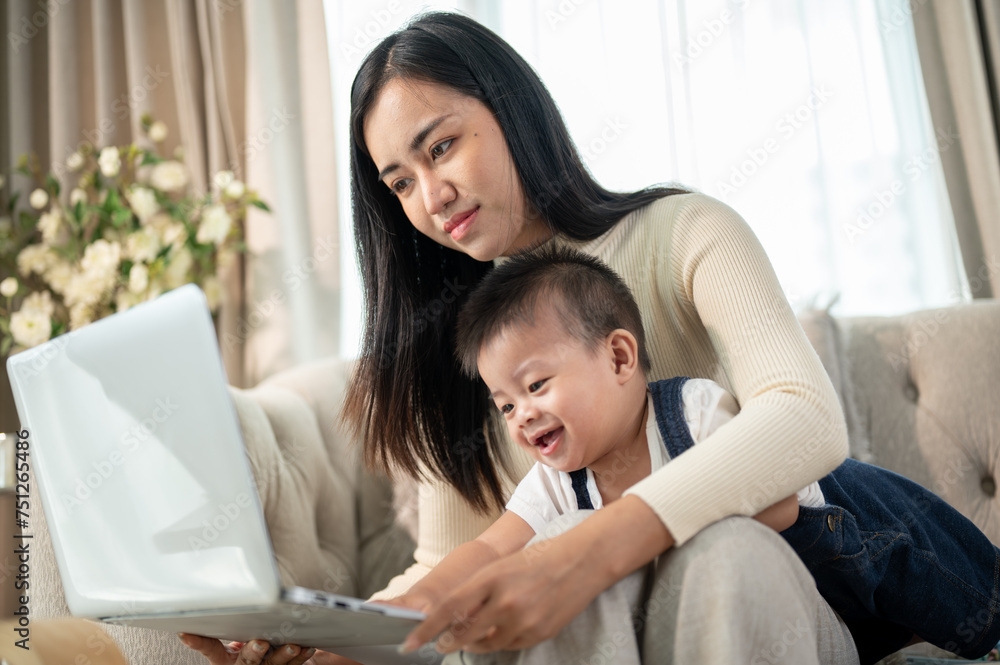 A happy Asian businesswoman mom is working from home and taking care of her naughty baby boy. A happy Asian businesswoman mom is working from home and taking care of her naughty baby boy.
