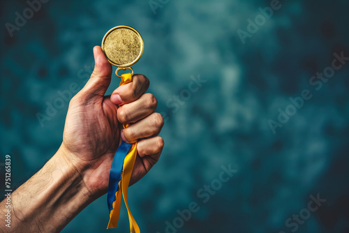 Triumphant Hand Raising Gold Medal Against Textured Blue Background Banner