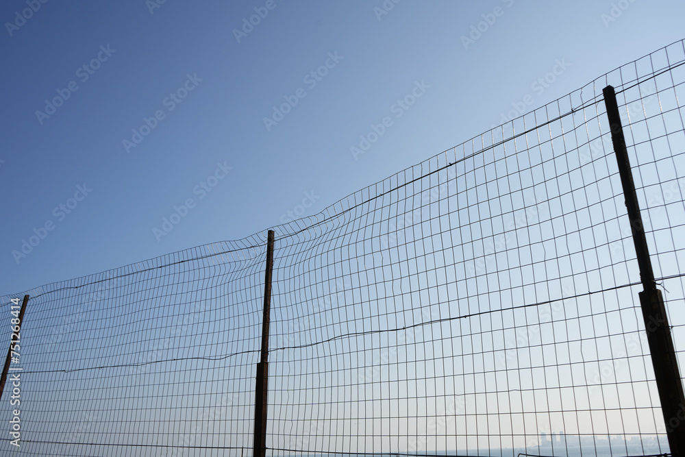 pattern or background of net over blue sky. silhouette of a ripped metallic net. wire fence made of thin wire against heaven. pattern or background of net over blue sky. silhouette of a ripped metallic net. wire fence made of thin wire against heaven.