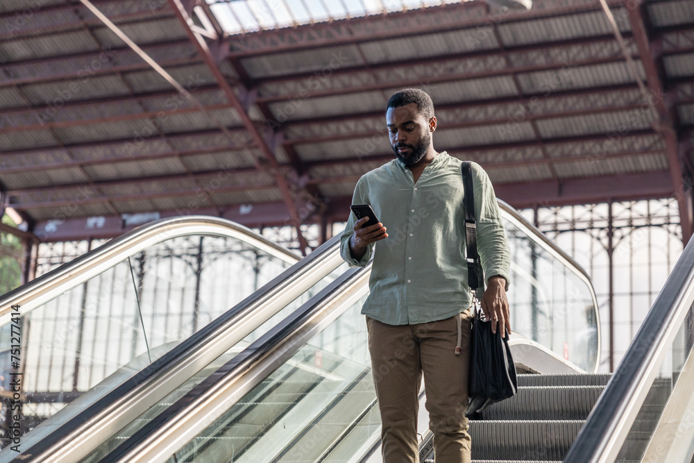 A man going down the escalators at the train station. A man going down the escalators at the train station.