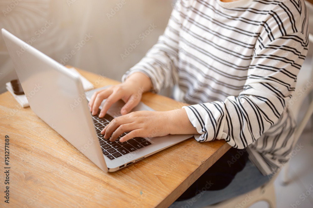 Naklejka premium A close-up image of a female freelancer working remotely at a coffee shop, working on her laptop.