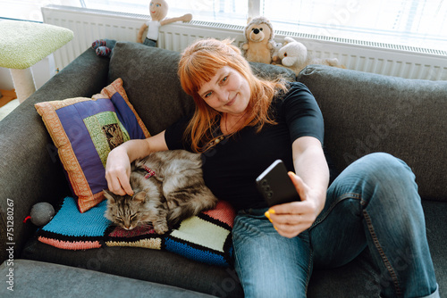 middle-aged woman spends time using phone with pet cat.