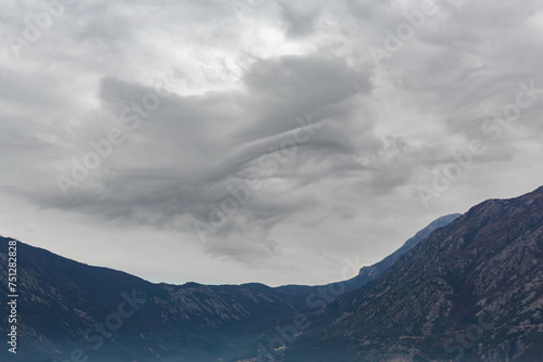 Dramatic undulating clouds hang over the mountainous landscape of Kotor Bay  signaling a change in weather