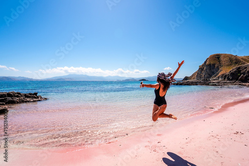 Young female tourism enjoying the tropical pink sandy beach with clear turquoise water at Komodo islands in Indonesia