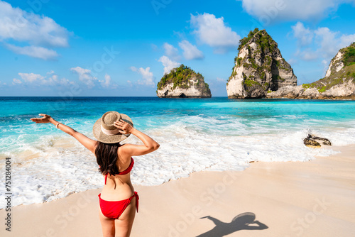 Young woman traveler relaxing and enjoying the beautiful tropical white sand beach at diamond beach in Nusa Penida island, Bali