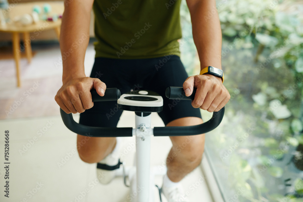 Cropped image of man wearing fitness tracker when working out on exercise bike