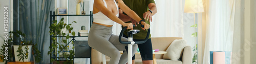 Cropped image of fitness trainer explaining client how to control heart beat on tracker when riding exercise bike