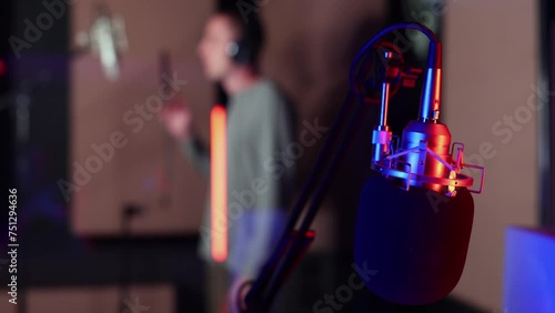 Young musician singing into a microphone while laying down tracks in a music studio