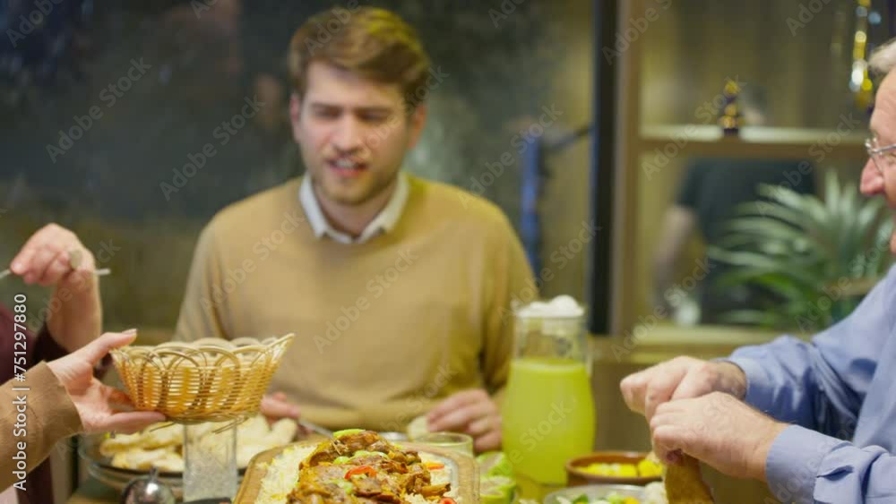 Muslim Woman in Hijab Sharing Bread with Other Family Members in Ramadan During Iftar Meal Muslim Woman in Hijab Sharing Bread with Other Family Members in Ramadan During Iftar Meal