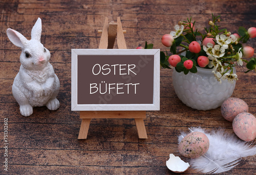 Der Text Osterbüfett auf eine Staffelei geschrieben mit Blumen und Osterdekoration.	