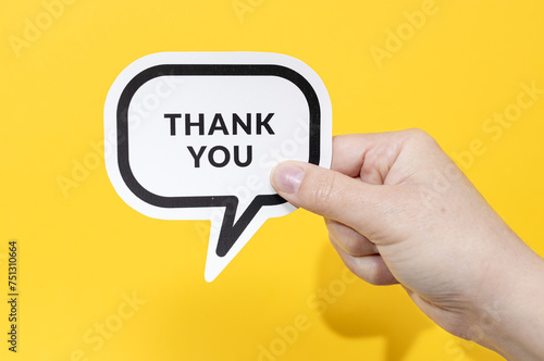 Hand holding speech bubble with Thank You text isolated on yellow background