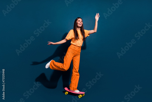 Full body size photo of young active and sportive lady ride penny board looking far away down street isolated on dark blue color background