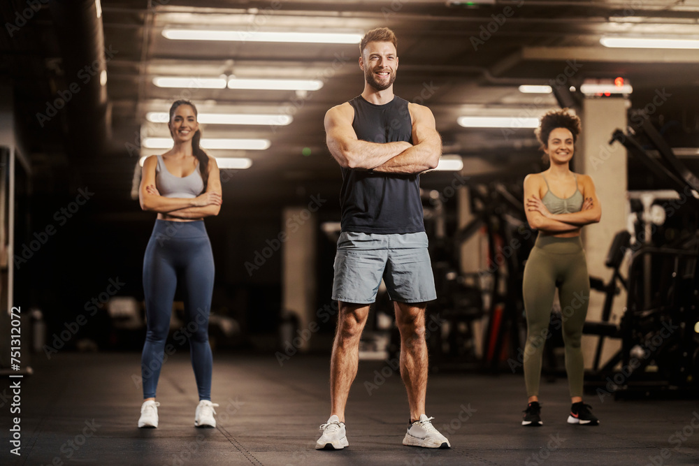 Sportspeople in shape are standing in a gym with arms crossed. Sportspeople in shape are standing in a gym with arms crossed.