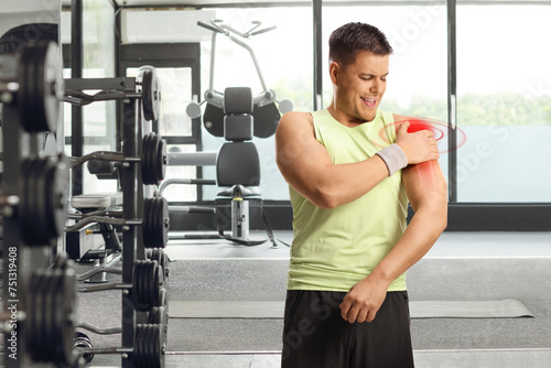 Man at a gym, holding his red painful shoulder