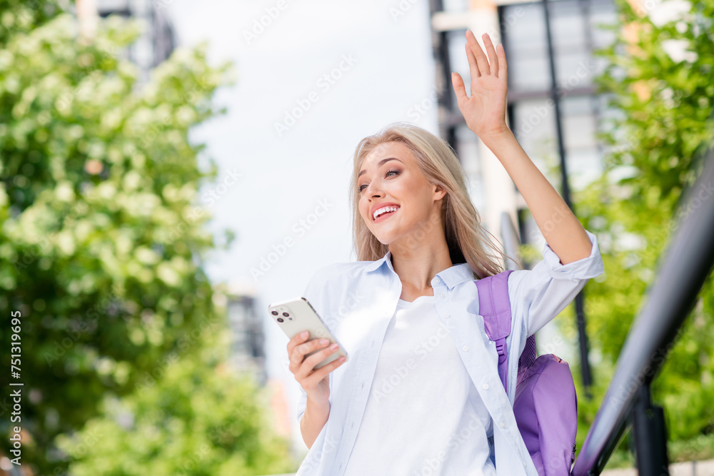 Photo of cheerful positive adorable girl going meet date with friend waving hand hi summer sunny day outdoors