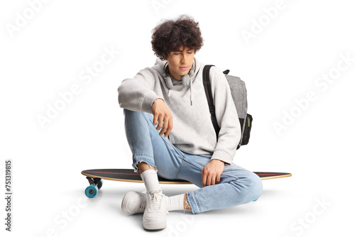 Pensive young man sitting on a skateboard