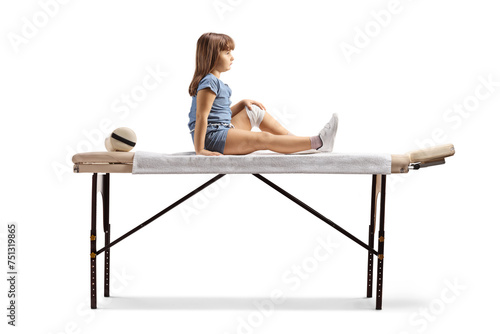 Full length profile shot of a child with leg injury sitting on a phycical therapy bed