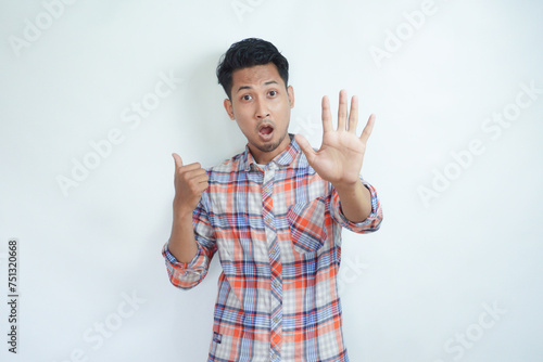 Adult Asian man making hand stop sign with worried expression while pointing to the right photo