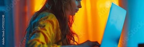 portrait of a woman looking a laptop computer, with an orange pattern background