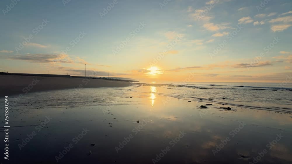 A tranquil scene captures waves crashing onto the shore, with sunset-hued clouds on the horizon, embodying the untouched beauty of nature's evening embrace.