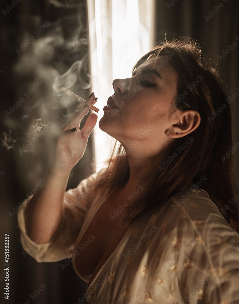 close-up of a beautiful girl smoking in her nightgown by the curtains, blowing smoke from her mouth. close-up of a beautiful girl smoking in her nightgown by the curtains, blowing smoke from her mouth.