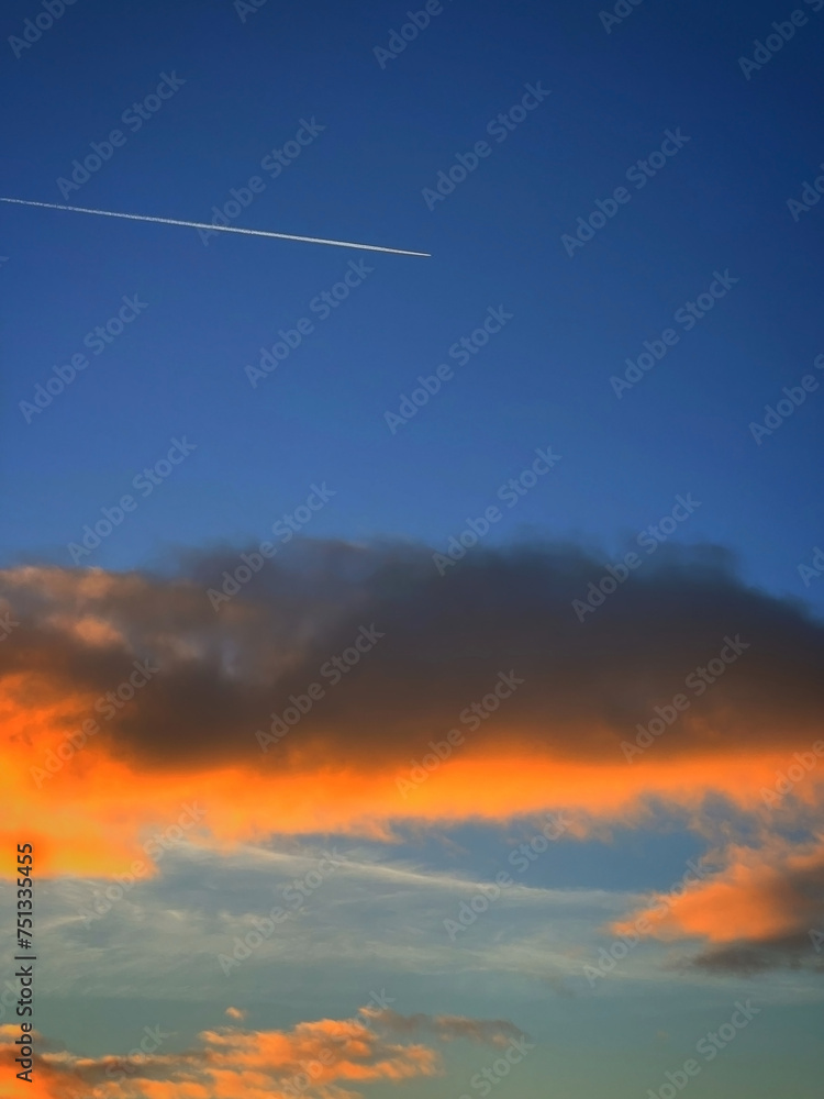 Airplane trace in the blue sky at sunset