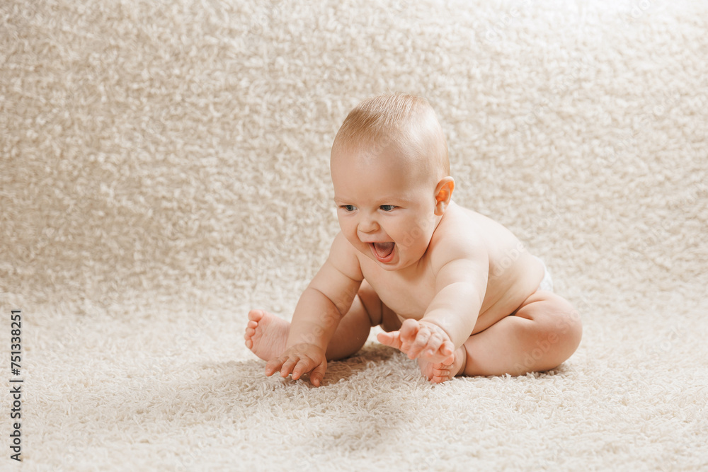 Portrait funny baby boy crawling indoors at home on white carpet background. Concept first step Portrait funny baby boy crawling indoors at home on white carpet background. Concept first step
