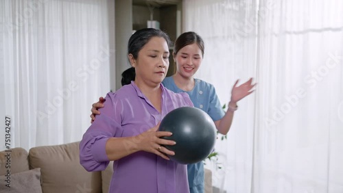 Asian Elderly woman holding a large massage ball used for rehabilitation in home,doing leg physiotherapy for elderly woman, to treat osteoarthritis and nerve pain in the leg,to nursing home concept photo