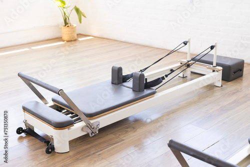 A Pilates reformer machine is ready for a workout in a bright studio photo
