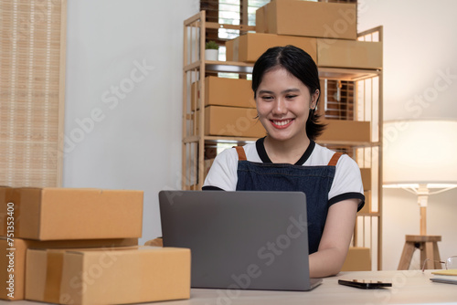 young female entrepreneur writes on the front of a product box to sell products online and prepares to send them to customers. Online selling at home, working from home