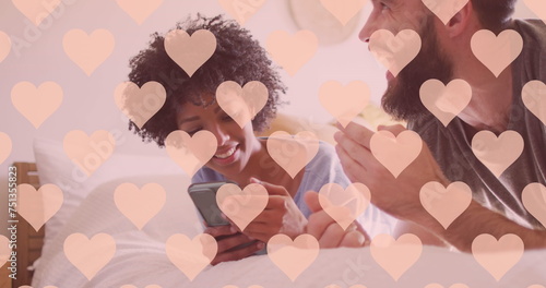 Image of hearts over happy diverse couple using smartphone