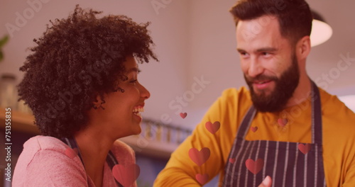 Image of hearts ove diverse couple preparing meal in kitchen