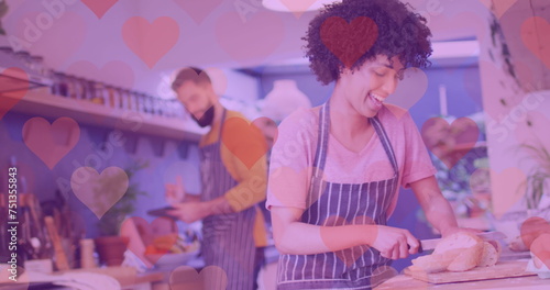 Image of hearts over happy diverse couple preparing meal